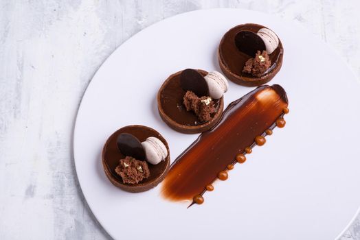 A closeup shot of a delicious chocolate dessert with macaroon served on a white plate