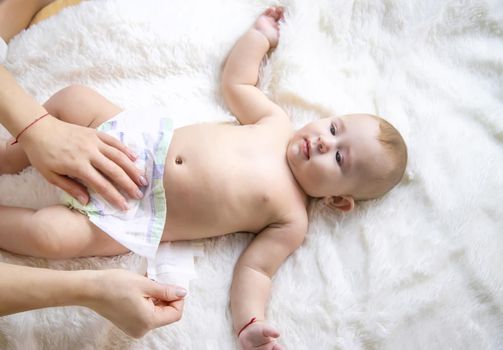 The mother is changing the baby's diaper. Selective focus. People.