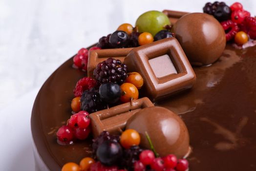 A close-up shot of a chocolate glaze cake decorated with berries.
