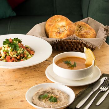 A closeup shot of a soup and appetizers near basket of breads