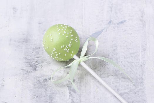 A green cake pop on a textured background