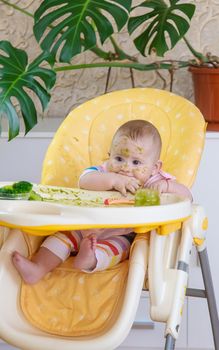 Little baby eats broccoli puree himself. Selective focus. People.