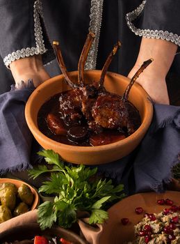 A vertical shot of a waitress presenting a tomahawk steak