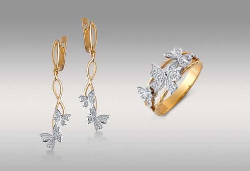 A closeup shot of the gold earrings and ring with diamond butterflies isolated on the white background