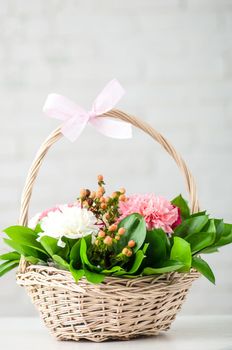 A vertical shot of a beautiful composition with white and pink peony roses in a straw basket