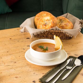 A closeup shot of a soup and appetizers near basket of breads