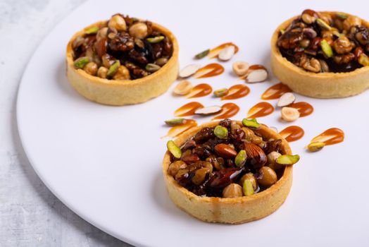 The appetizing tartlets stuffed with hazelnuts walnuts covered with a layer of liquid caramel