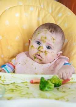 Little baby eats broccoli puree himself. Selective focus. People.