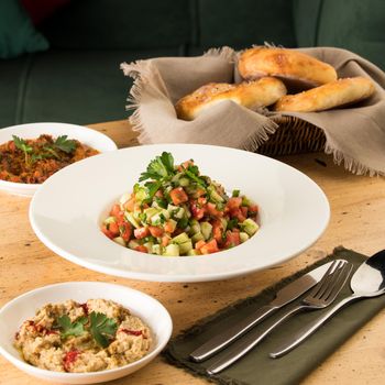 A close up shot of salads and appetizers near basket of breads