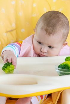 Little baby is eating broccoli vegetable puree. Selective focus. People.