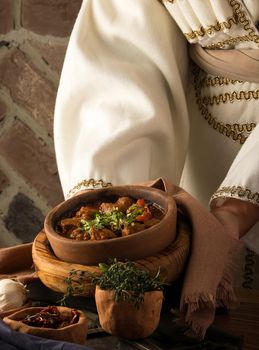 A vertical shot of a waitress presenting a meat stew