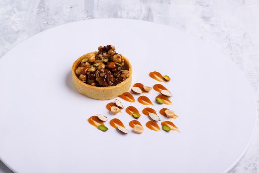 The appetizing tartlets stuffed with hazelnuts walnuts covered with a layer of liquid caramel