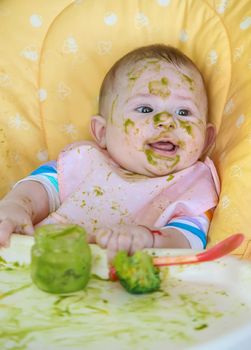 Little baby eats broccoli puree himself. Selective focus. People.