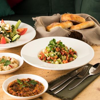 A close up shot of salads and appetizers near basket of breads