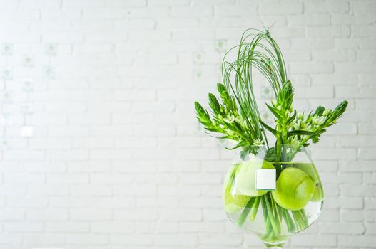 A closeup shot of Ornithogalum plant and apples in a large glass cup on a table