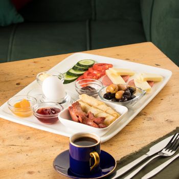 A closeup shot of a breakfast white plate and a cup of coffee on a wooden table