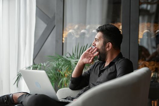 thoughtful entrepreneur with a laptop sitting in an armchair . business concept.