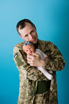 Ukrainian military man father with newborn baby girl on blue isolated background during war in Ukraine 2022