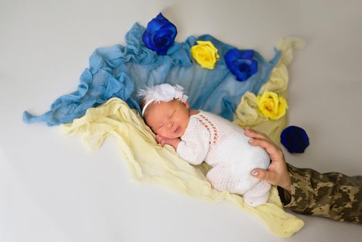 Ukrainian newborn in the studio patriotic blue yellow colors during the war in Ukraine 2022. A little baby, girl sleeps with mother military