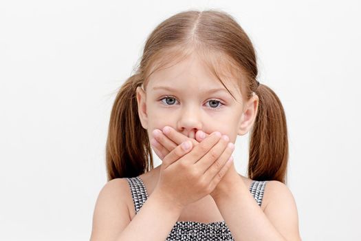 Caucasian little girl of 6 years holding hands on mouth showing difficulty in speaking as dysarthria on white background