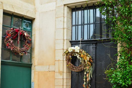 Wreaths with the red berries blackberry and the dry leaves hanging on a doors.