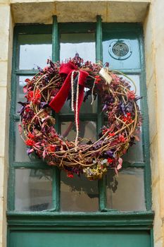 Wreath with the red berries blackberry and the dry leaves hanging on a door.