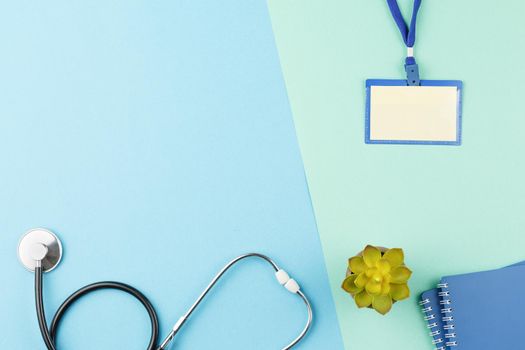 Stethoscope with badge and spiral notebooks on color isolated background. Top view medical worker desktop concept. Flat lay with copy space.