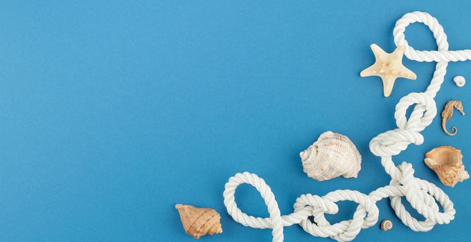Starfish with seashells on blue background. Photo top view with copy space. Concept of beach holiday on the coast. Marine rope with seahorse. Flat lay.