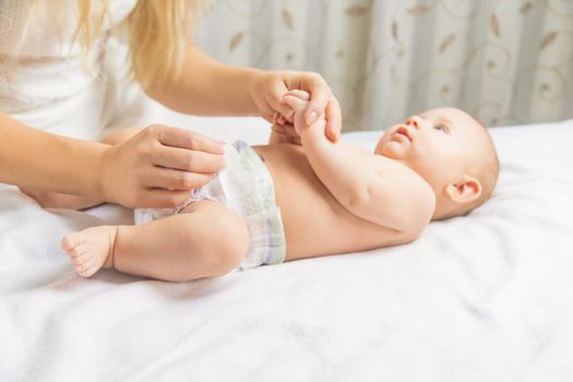 The mother changes the baby's diaper. Selective focus. People.