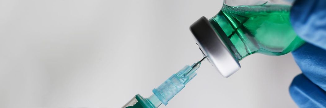 Close-up of medical worker gather liquid from glass bottle in syringe. Preparing for vaccination against coronavirus. Medicine, vaccine, save life concept