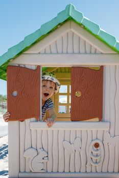 The emotion of a small child playing hide and seek. The boy was hiding in a small house