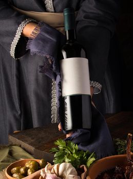 A vertical shot of a person in a traditional costume showing a wine bottle