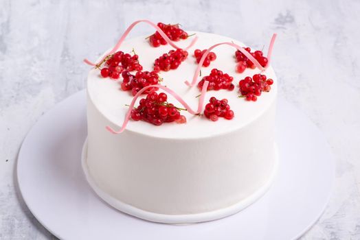 A top view shot of a white cake designed by red berry on a white plate