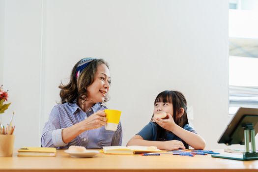 Asian portrait, grandchild granddaughter grandma grandmother and granddaughter happily join in activities to enjoy eating and enhance skills for grandchildren.