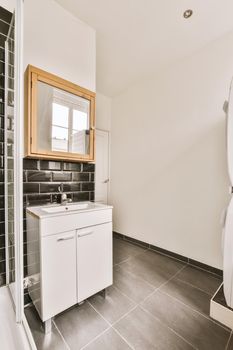 Fragment of interior of modern white bathroom with wooden cabinet under sink and with mirror