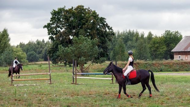 Young girls dressage their horses before the competition in stud farm.