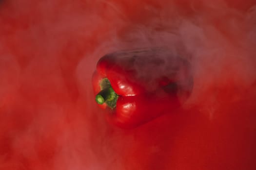 SWEET, fresh RED PEPPER ON A RED BACKGROUND WITH A LIGHT SMOKE.