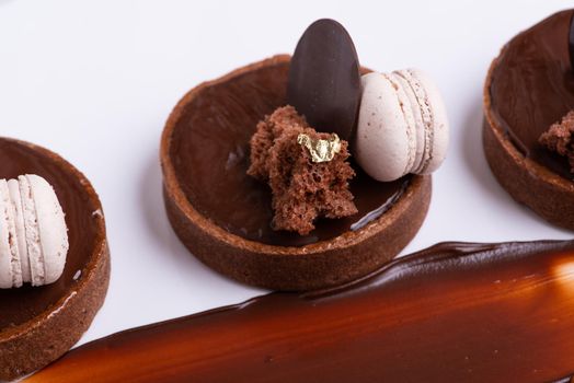 A closeup shot of a delicious chocolate dessert with macaroon served on a white plate