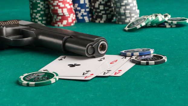 A close-up shot of a weapon next to some playing cards and poker chips on a green board.