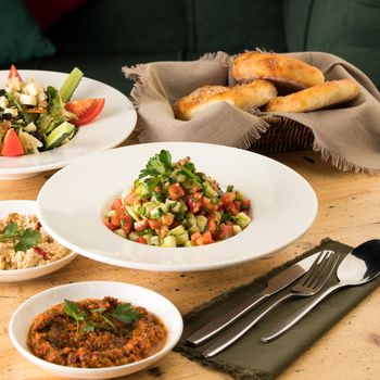 A close up shot of salads and appetizers near basket of breads