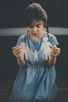 Child with a paper family in his hands. the concept of divorce, custody and child abuse. Selective focus. People.