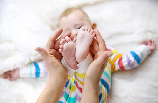 The mother holds the legs of her baby. Selective focus. Child.