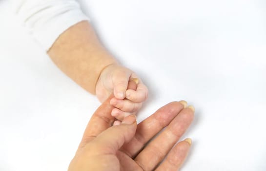 Baby hands with mom's hands against white background. Selective focus. People.