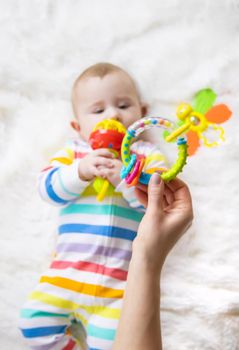 The mother gives a rattle to the baby. Selective focus. child.