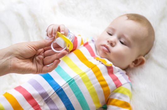 The mother gives the baby a pacifier. Selective focus. Child.