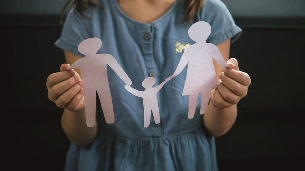 Child with a paper family in his hands. the concept of divorce, custody and child abuse. Selective focus. People.