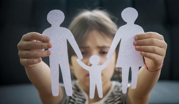 Child with a paper family in his hands. the concept of divorce, custody and child abuse. Selective focus. People.