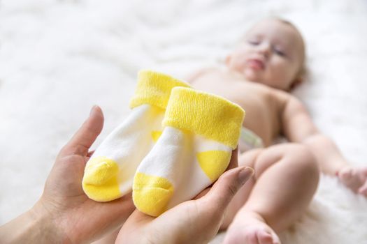 Mother puts socks on the little baby. Selective focus. People.