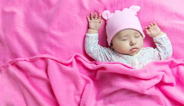 Baby sleeps on a pink bed. Selective focus. people.