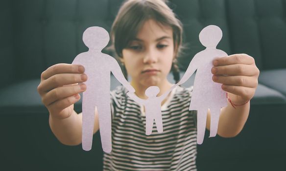 Child with a paper family in his hands. the concept of divorce, custody and child abuse. Selective focus. People.